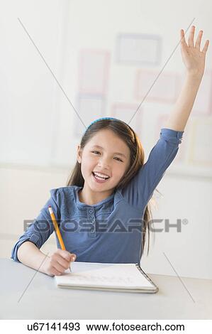Stock Image - Portrait of schoolgirl (8-9) raising hand. Fotosearch