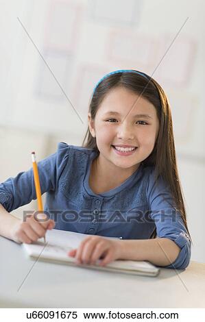 Stock Photography - Portrait of schoolgirl (8-9) writing in notebook. Fotosearch