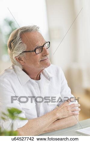Stock Image - Portrait of senior man sitting at desk. Fotosearch