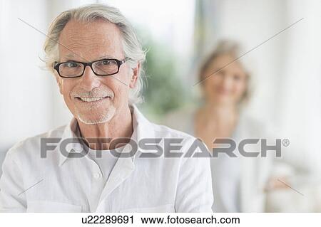 Portrait of senior man, woman in background View Large Photo Image Stock Image - Portrait of senior man, woman in background. Fotosearch