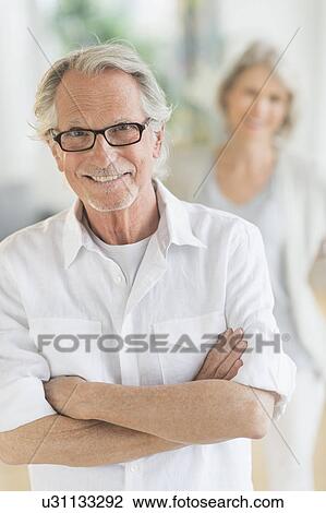 Stock Image - Portrait of senior man, woman in background. Fotosearch