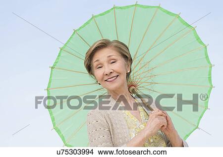 Portrait of senior woman holding green parasol View Large Photo Image Picture - Portrait of senior woman holding green parasol. Fotosearch