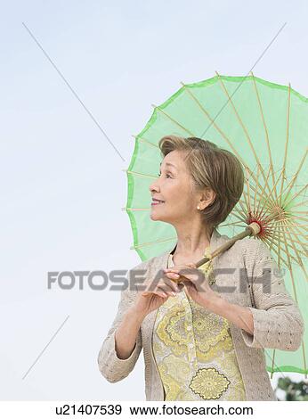 Portrait of senior woman holding green parasol View Large Photo Image Stock Photo - Portrait of senior woman holding green parasol. Fotosearch