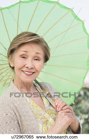 Stock Photography - Portrait of senior woman holding green parasol. Fotosearch