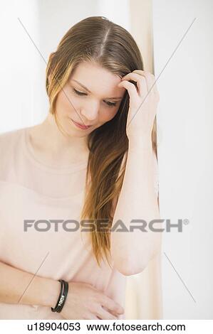Stock Image - Portrait of smiling woman with hand in hair. Fotosearch