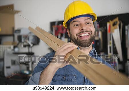 Portrait of smiling worker, holding boards on his shoulder View Large Photo Image Picture - Portrait of smiling worker, holding boards on his shoulder. Fotosearch