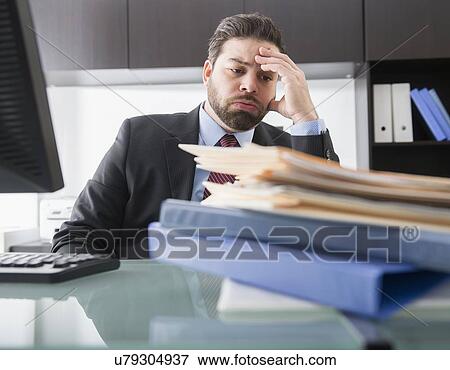 Stock Photo - Portrait of tired businessman sitting in office. Fotosearch