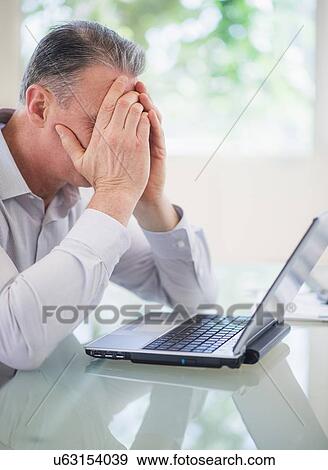 Stock Photo - Portrait of tired man working on laptop. Fotosearch