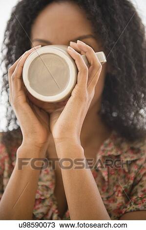 Stock Image - Portrait of woman drinking from coffee mug. Fotosearch