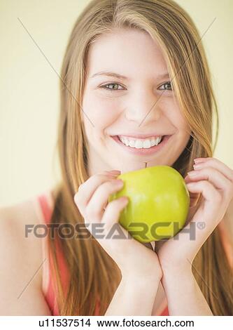 Picture - Portrait of woman holding apple. Fotosearch