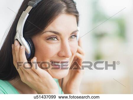Stock Photo - Portrait of woman listening to music on headphones. Fotosearch