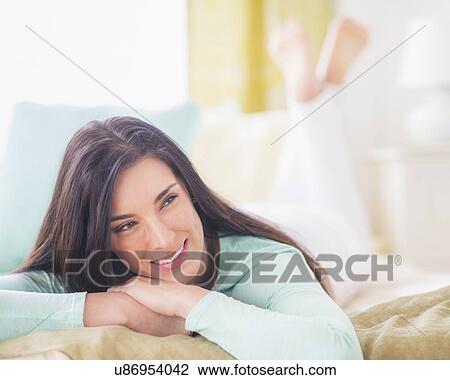 Portrait of woman lying down on bed with hand on chin, Looking away, Close-up View Large Photo Image Stock Image - Portrait of woman lying down on bed with hand on chin, Looking away, Close-up. Fotosearch