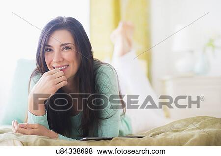 Portrait of woman lying down on bed with hand on chin View Large Photo Image Stock Photo - Portrait of woman lying down on bed with hand on chin. Fotosearch