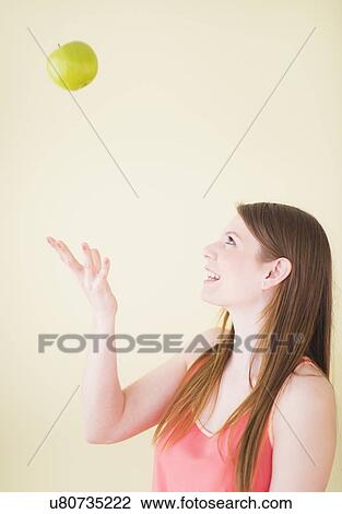Stock Image - Portrait of woman playing with apple. Fotosearch