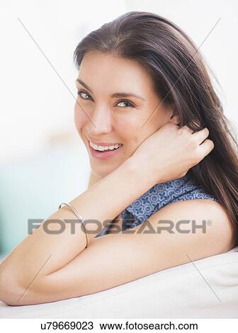 Stock Image - Portrait of woman relaxing on sofa. Fotosearch