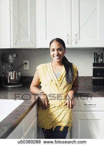Stock Photo - Portrait of woman standing in kitchen. Fotosearch