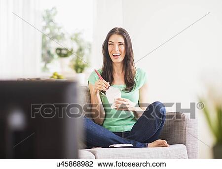 Portrait of woman watching tv and eating take out food View Large Photo Image Stock Image - Portrait of woman watching tv and eating take out food. Fotosearch