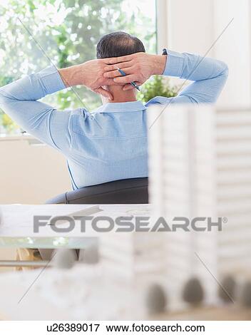 Stock Photo - Rear view of man sitting in office. Fotosearch