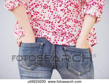 Stock Image - Rear view of woman with hands in pocket. Fotosearch