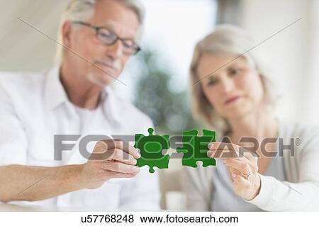 Stock Photo - Senior couple holding matching jigsaw pieces. Fotosearch