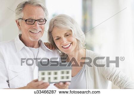 Senior couple holding model house View Large Photo Image Stock Photo - Senior couple holding model house. Fotosearch