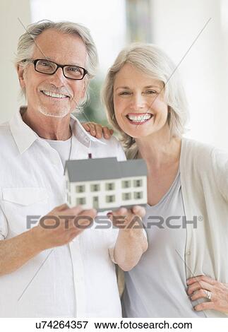 Senior couple holding model house View Large Photo Image Stock Photo - Senior couple holding model house. Fotosearch