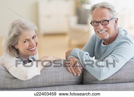 Stock Photo - Senior couple sitting on sofa. Fotosearch