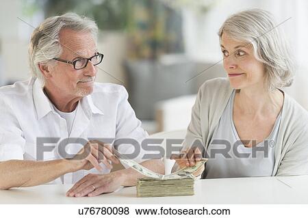 Senior couple taking money from banknotes stack View Large Photo Image Stock Photo - Senior couple taking money from banknotes stack. Fotosearch