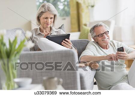 Senior couple using digital tablet and cell phone at home View Large Photo Image Stock Photo - Senior couple using digital tablet and cell phone at home. Fotosearch