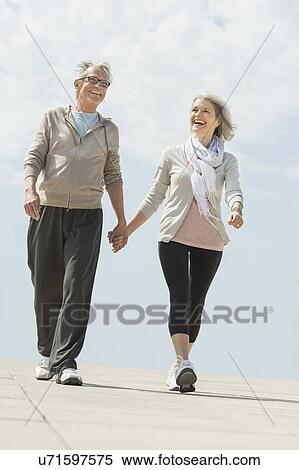 Stock Photography - Senior couple walking and holding hands. Fotosearch