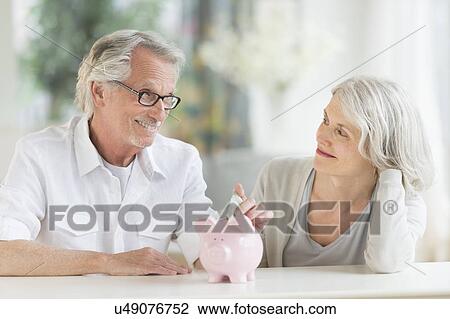 Stock Image - Senior couple with piggybank. Fotosearch