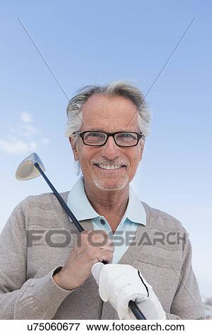 Stock Photo - Senior man holding golf club. Fotosearch