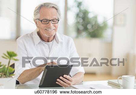 Stock Photograph - Senior man using digital tablet. Fotosearch