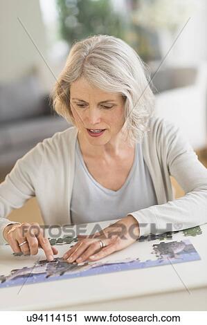 Senior woman completing jigsaw puzzle View Large Photo Image Stock Image - Senior woman completing jigsaw puzzle. Fotosearch