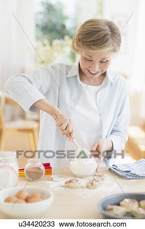Stock Image - Senior woman cooking in kitchen. Fotosearch