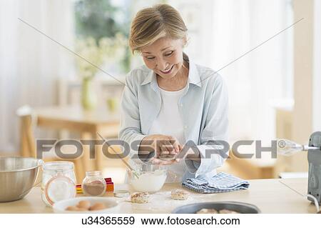 Stock Photo - Senior woman cooking in kitchen. Fotosearch