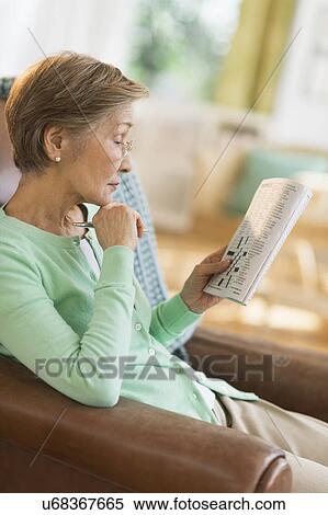 Stock Photography - Senior woman doing crossword puzzle. Fotosearch