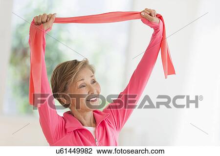 Stock Image - Senior woman exercising with exercise band. Fotosearch