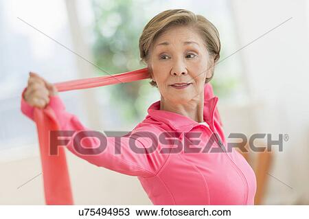Stock Image - Senior woman exercising with exercise band. Fotosearch