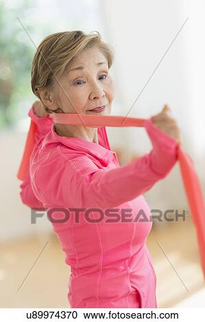 Stock Image - Senior woman exercising with exercise band. Fotosearch