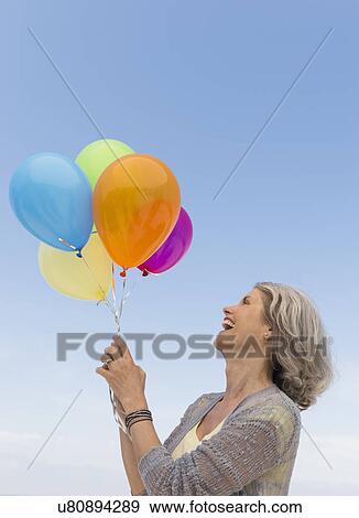 Senior woman holding bunch of colorful balloons View Large Photo Image Stock Photo - Senior woman holding bunch of colorful balloons. Fotosearch