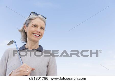 Stock Photograph - Senior woman holding golf club. Fotosearch