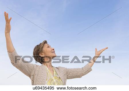 Stock Photography - Senior woman looking up at blue sky. Fotosearch