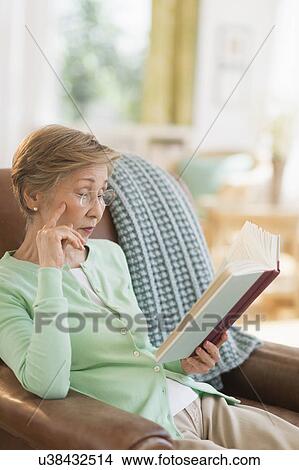 Picture - Senior woman reading book at home. Fotosearch