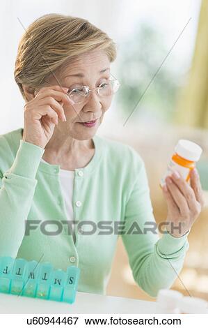 Stock Photo - Senior woman reading medicine label. Fotosearch