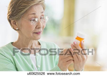 Stock Photograph - Senior woman reading medicine label. Fotosearch