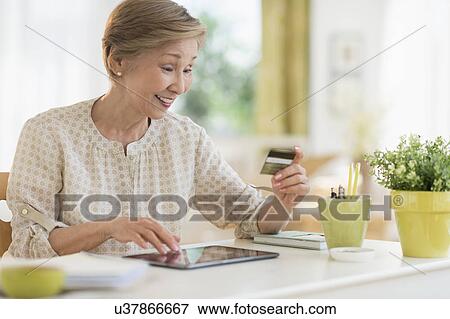 Stock Photo - Senior woman shopping online with tablet pc. Fotosearch