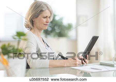 Stock Image - Senior woman using digital tablet. Fotosearch