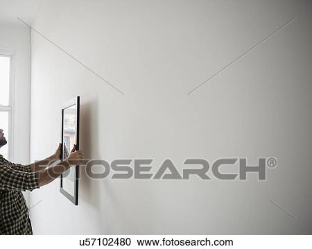 Side view of man hanging picture on wall View Large Photo Image Stock Image - Side view of man hanging picture on wall. Fotosearch
