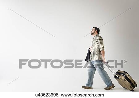 Stock Photograph - Side view of man walking with suitcase. Fotosearch